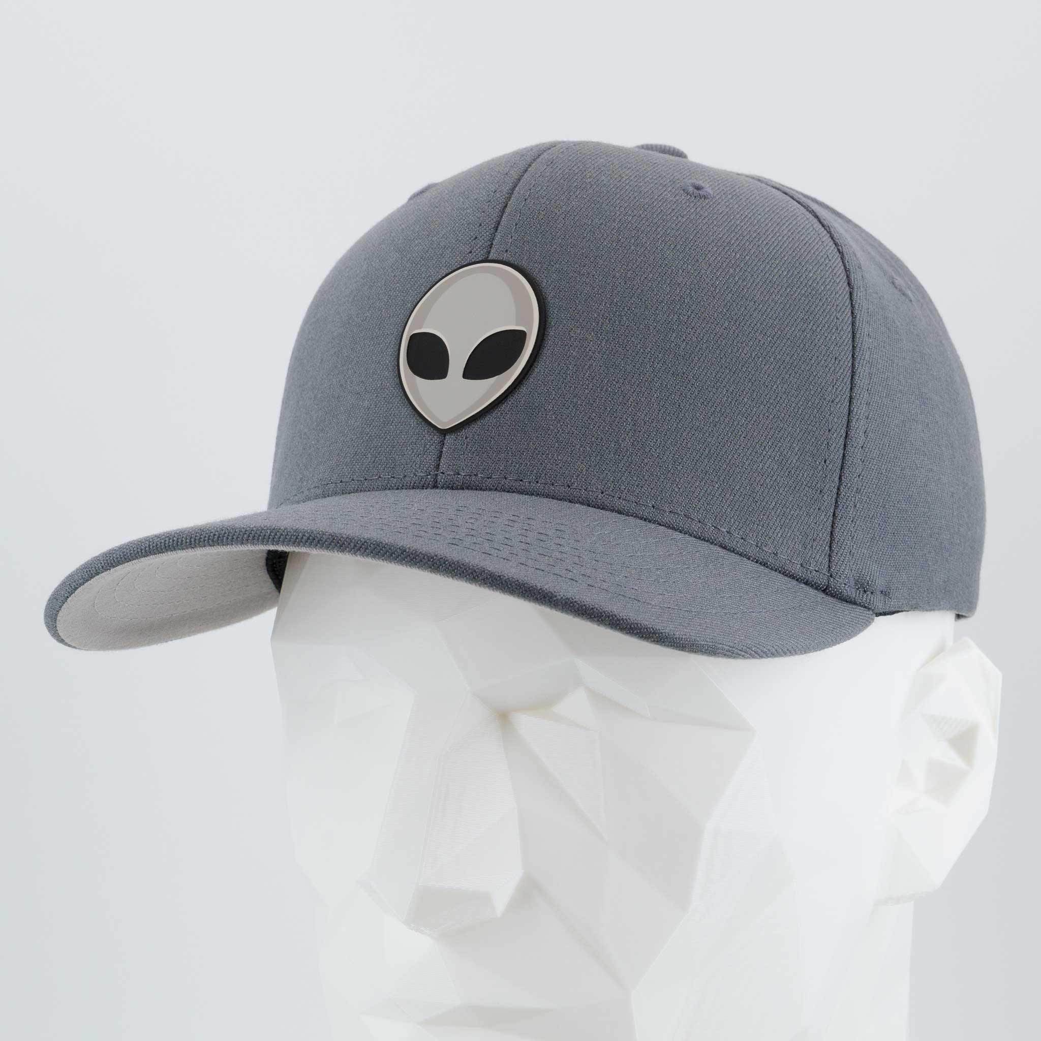 The Alien Gray (Double Layer Silicone) Flexfit® Premium Wool Blend Cap by Eternal Glyph, featuring a black and white alien face logo, rests on a white faceted mannequin head against a plain light background.