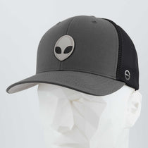The Eternal Glyph Alien Gray (Double Layer Silicone) Flexfit® Mesh Trucker Cap features a matte gray and black design with a metallic grey alien emblem, inspired by UFO pop culture, shown on a white geometric mannequin head.