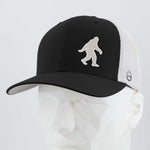 The Eternal Glyph Bigfoot Silhouette Albino (Silicone) Flexfit® Mesh Trucker Cap, featuring a black and white design and Bigfoot patch inspired by Pacific Northwest folklore, is shown on a faceted white mannequin head.
