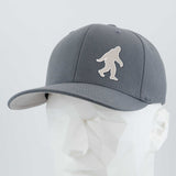 The Eternal Glyph Bigfoot Silhouette Albino Flexfit® Premium Wool Blend Cap features a white Bigfoot logo, inspired by Pacific Northwest folklore, shown on a white geometric mannequin head against a light gray background.