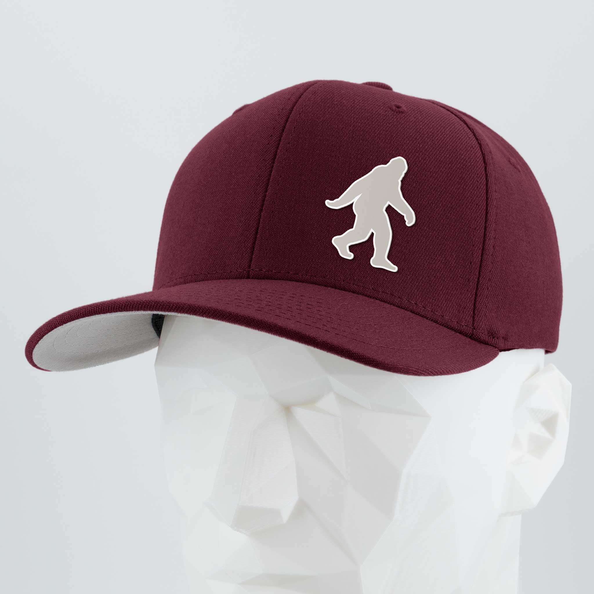 Showcased on a white geometric mannequin, the Eternal Glyph "Bigfoot Silhouette Albino" Flexfit® Premium Wool Blend Cap features a bold white Sasquatch glyph—ideal for Pacific Northwest folklore fans.
