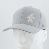 The Eternal Glyph Bigfoot Silhouette Albino (Silicone) Flexfit® Cool & Dry Cap is a light gray cap with a white Bigfoot silhouette, inspired by Pacific Northwest folklore, shown on a white geometric mannequin head.