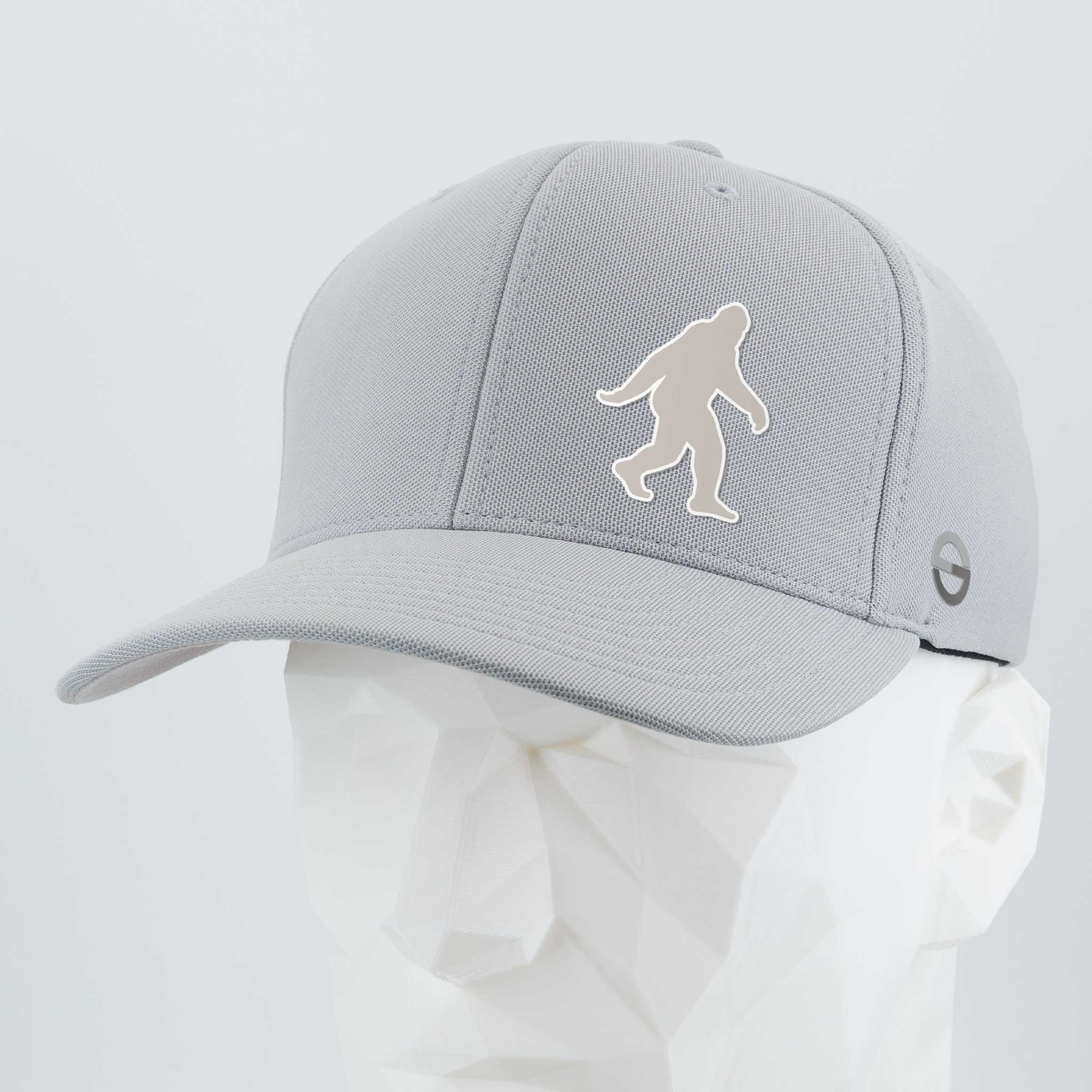 The Eternal Glyph Bigfoot Silhouette Albino (Silicone) Flexfit® Cool & Dry Cap is a light gray cap with a white Bigfoot silhouette, inspired by Pacific Northwest folklore, shown on a white geometric mannequin head.