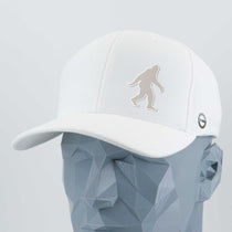 The Eternal Glyph Bigfoot Silhouette Albino Flexfit® Cool & Dry Cap features a bold Bigfoot design on white silicone, shown on a faceted gray mannequin. A small circular logo adds Pacific Northwest flair to this unique accessory.