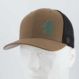 The Eternal Glyph Bigfoot Silhouette (Silicone) Flexfit® Mesh Trucker Cap in brown and black features a green Bigfoot icon on the front, shown here on a white geometric mannequin head.