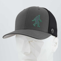 The Eternal Glyph Bigfoot Silhouette (Silicone) Flexfit® Mesh Trucker Cap features a gray and black mesh back and a green Bigfoot icon, modeled on a white mannequin—perfect for outdoor enthusiasts.