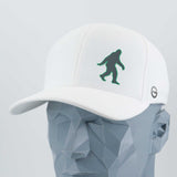 The Eternal Glyph Bigfoot Silhouette (Silicone) Flexfit® Cool & Dry Cap is a white baseball hat with a dark green Bigfoot design, shown on a faceted gray mannequin head—ideal for fans of this legendary wilderness icon.
