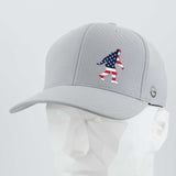 The Eternal Glyph Patriotic Bigfoot (Silicone) Flexfit® Cool & Dry Cap is a light gray baseball cap with an American flag-themed Bigfoot design, shown on a white geometric mannequin. Ideal for wilderness folklore fans.