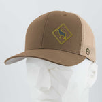 The Eternal Glyph Bighorn Sheep Crossing Sign (Silicone) Flexfit® Mesh Trucker Cap, in brown and beige mesh, features a yellow diamond patch with a bighorn sheep silhouette and is shown on a white geometric mannequin head.
