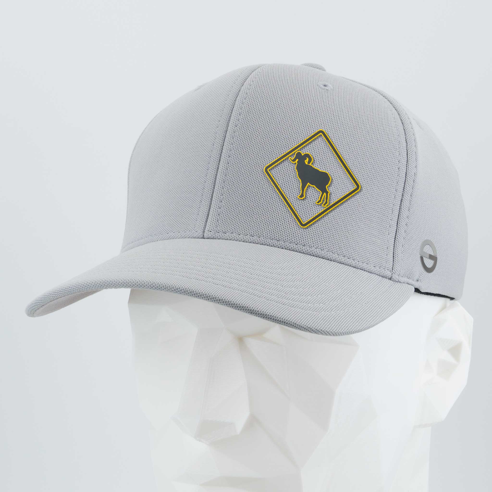 The Eternal Glyph Bighorn Sheep Crossing Sign (Silicone) Flexfit® Cool & Dry Cap is a light gray hat with a yellow diamond bighorn sheep patch and a small circular logo, shown on a white geometric mannequin head.