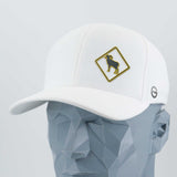 A geometric gray mannequin head displays the Eternal Glyph Bighorn Sheep Crossing Sign (Silicone) Flexfit® Cool & Dry Cap—white, with a yellow-bordered patch showing a black bighorn sheep silhouette and a small gray circular side logo.