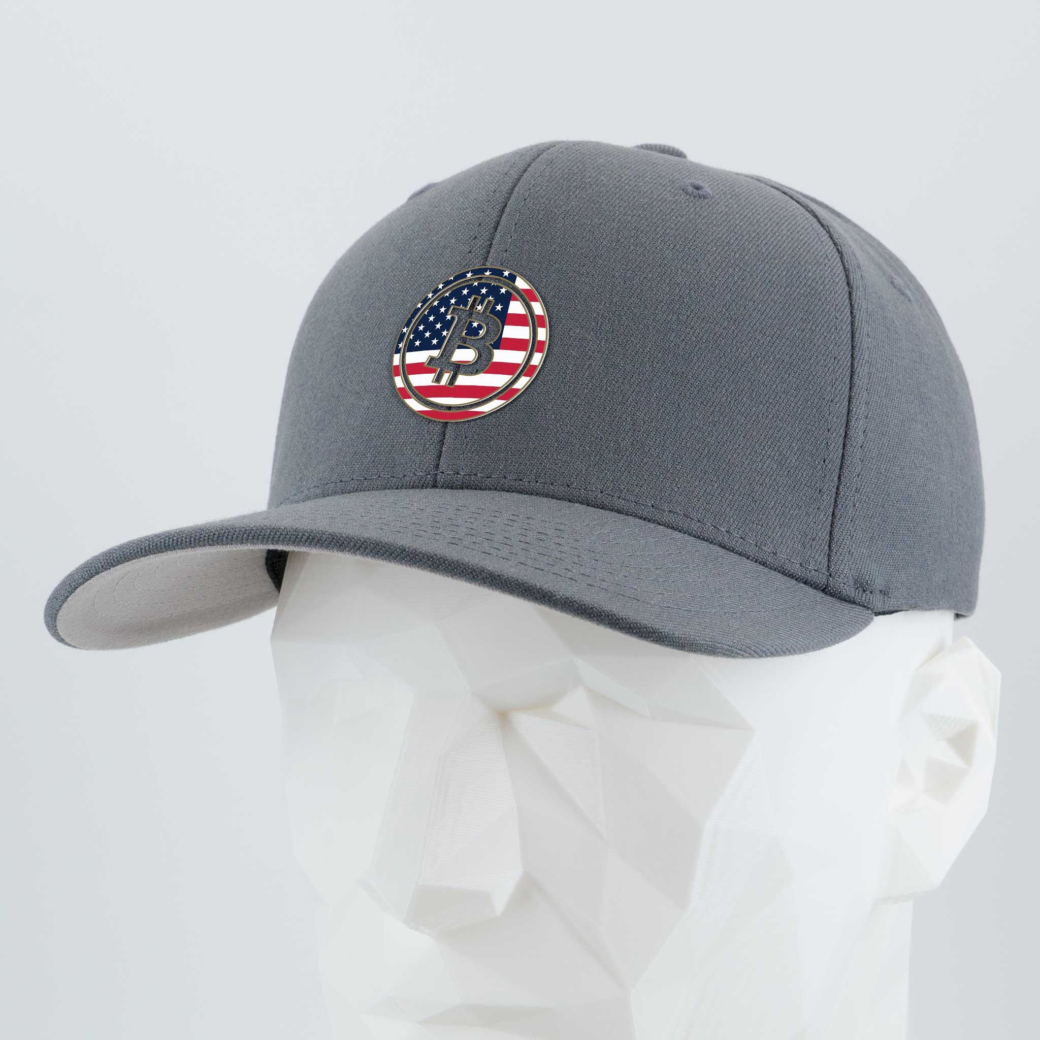 The Eternal Glyph Bitcoin U.S.A. (Silicone) Flexfit® Premium Wool Blend Cap, in gray, features a Bitcoin glyph with an American flag pattern—symbolizing financial freedom—shown on a white geometric mannequin against a plain background.