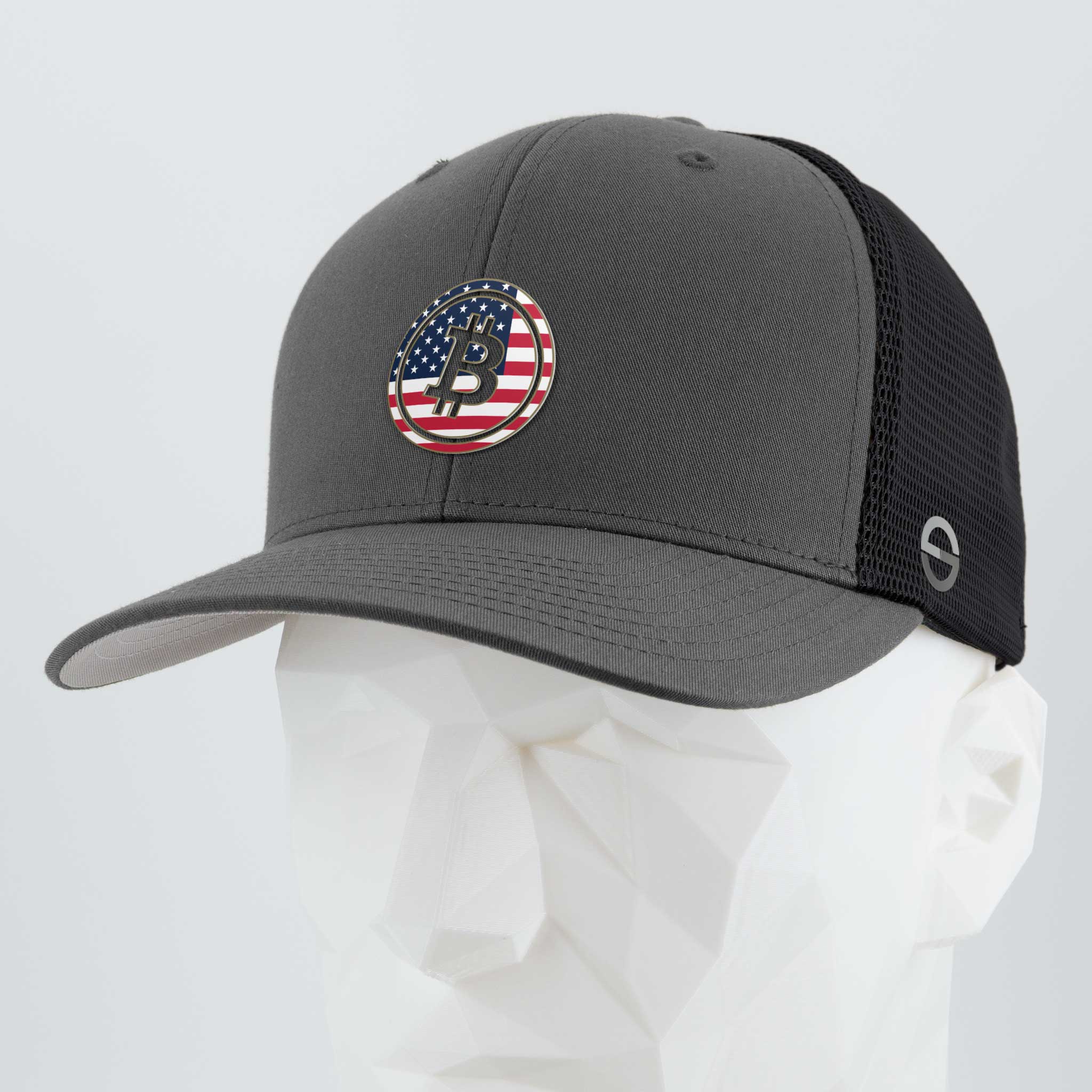 The Eternal Glyph Bitcoin U.S.A. (Silicone) Flexfit® Mesh Trucker Cap in Dark Gray/Black features a mesh back and circular patch with a Bitcoin glyph over an American flag, displayed on a faceted white mannequin head.