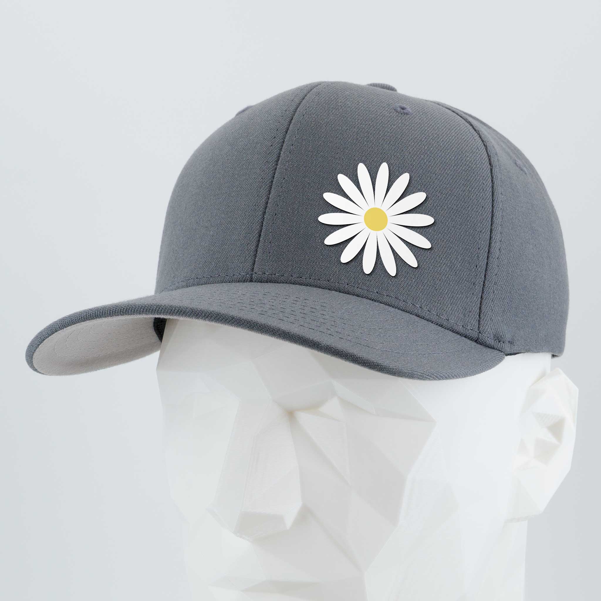 The Daisy (Silicone) - Flexfit® Premium Wool Blend Cap by Eternal Glyph: a gray cap with a white daisy and yellow center, shown on a white geometric mannequin head—a stylish everyday hat symbolizing optimism.