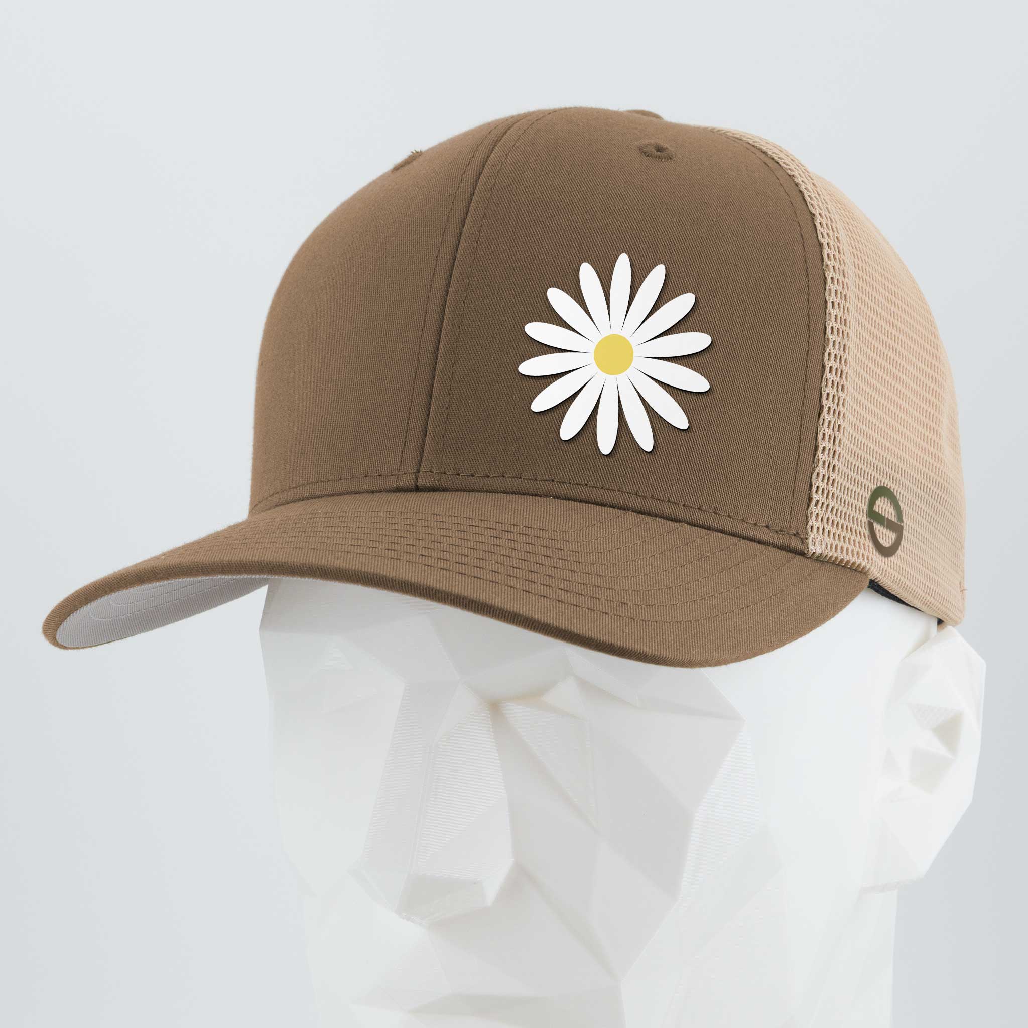 The Daisy (Silicone) - Flexfit® Mesh Trucker Cap by Eternal Glyph is a brown and beige hat featuring a white daisy on the front—an everyday symbol of optimism for your wardrobe. Displayed here on a white geometric mannequin head.