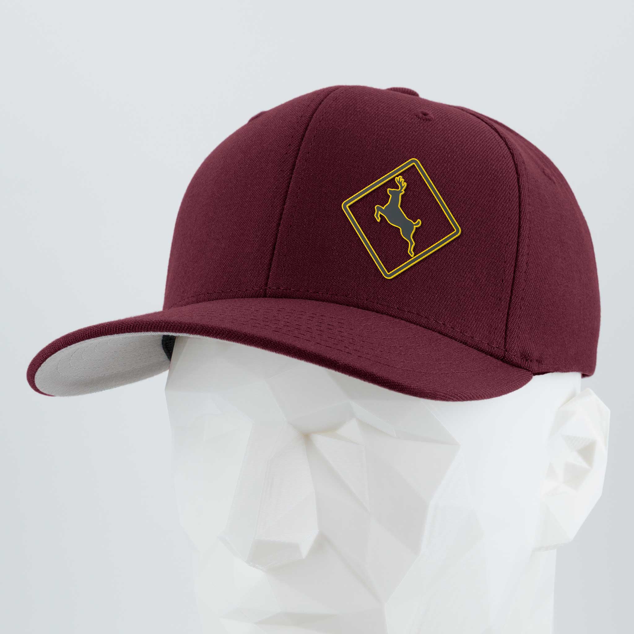 The Eternal Glyph Deer Crossing Sign (Silicone) - Flexfit® Premium Wool Blend Cap, featuring a yellow embroidered deer in a diamond emblem, is shown on a white geometric mannequin head against a plain gray backdrop.
