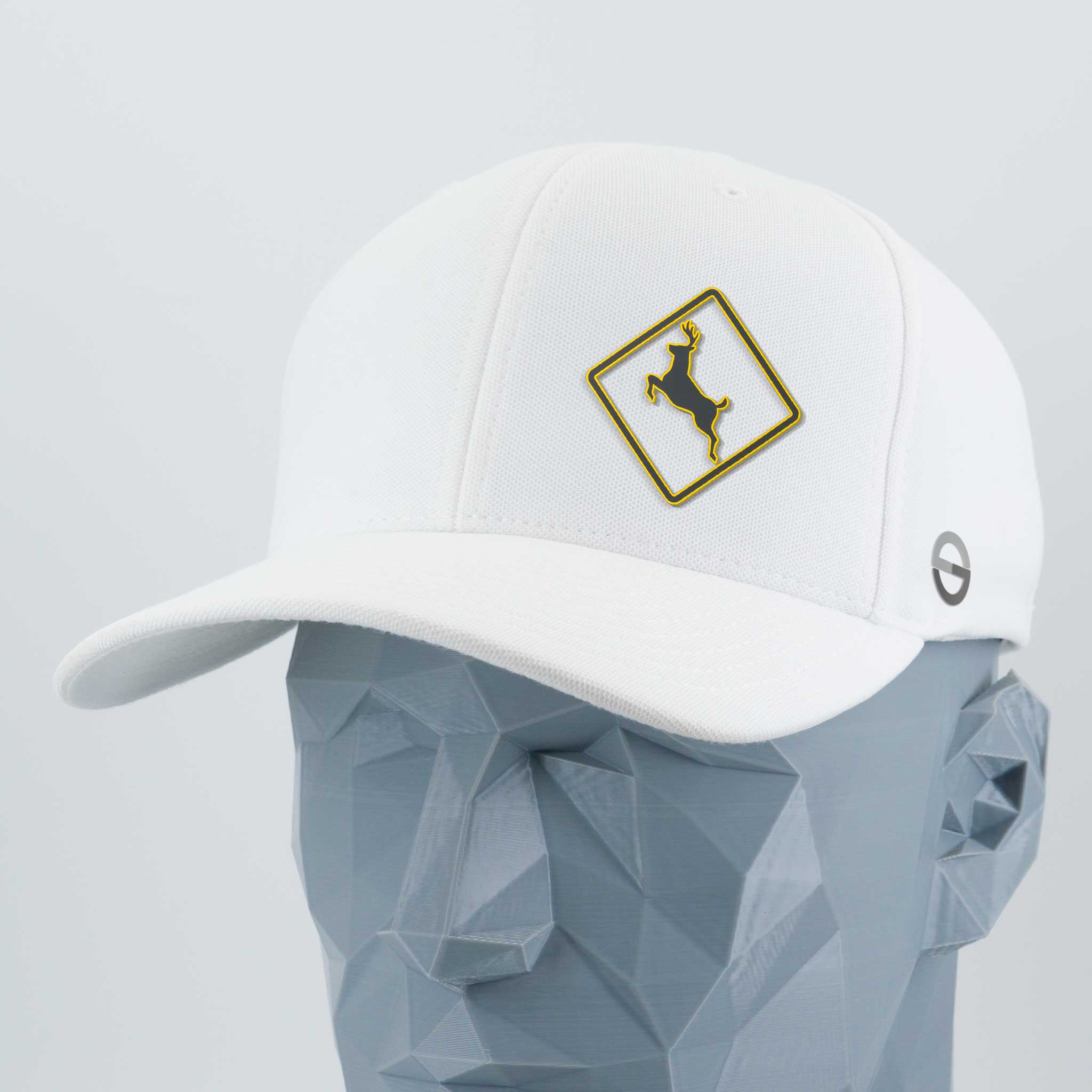 A geometric gray mannequin head models Eternal Glyph’s Deer Crossing Sign (Silicone) Flexfit® Cool & Dry Cap, a white hat with a gold-trimmed diamond patch featuring a leaping deer and a small circular side logo.