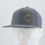 Eternal Glyph’s Elk Crossing Sign (Silicone) Flexfit® Flat Bill Premium Fitted Cap in gray features a yellow-outlined deer patch and text, shown on a white geometric mannequin head against a plain background.