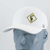 The Eternal Glyph Elk Crossing Sign (Silicone) - Flexfit® Cool & Dry Cap, a white hat with a gold-trimmed diamond patch featuring a black deer head, is shown on a geometric gray mannequin head.