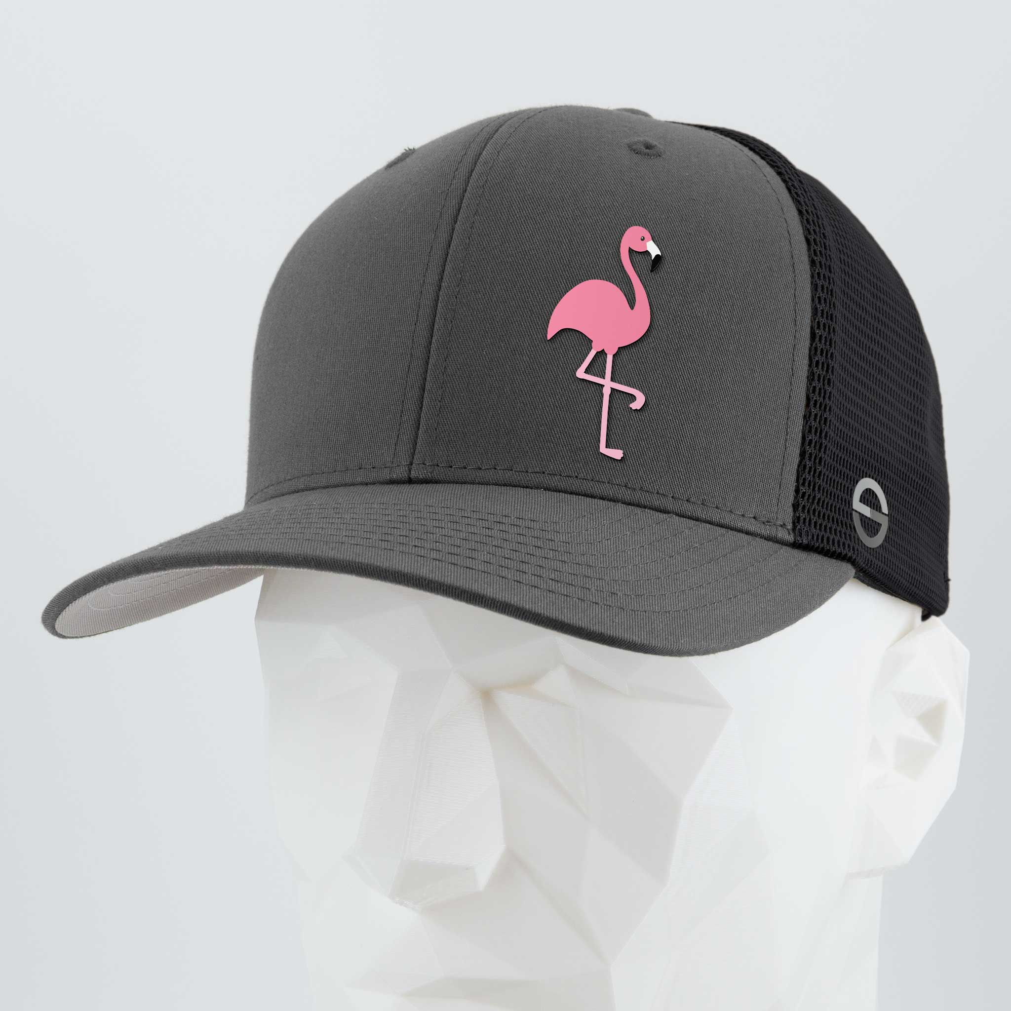 The Eternal Glyph Pink Flamingo (Silicone) Flexfit® Mesh Trucker Cap in Dark Gray/Black features a pink flamingo glyph for retro summer vibes, shown on a faceted white mannequin against a plain background.