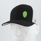 The Eternal Glyph Hop Cone (Silicone) - Flexfit® Mesh Trucker Cap features a black and white design, breathable mesh back, and a green Hop Cone Symbol up front—ideal for beer enthusiasts. Shown on a white geometric mannequin head.