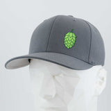 The Eternal Glyph Hop Cone (Silicone) Flexfit® Premium Wool Blend Cap features a green hop cone symbol on the front, displayed on a white geometric mannequin—an ideal accessory for beer enthusiasts.