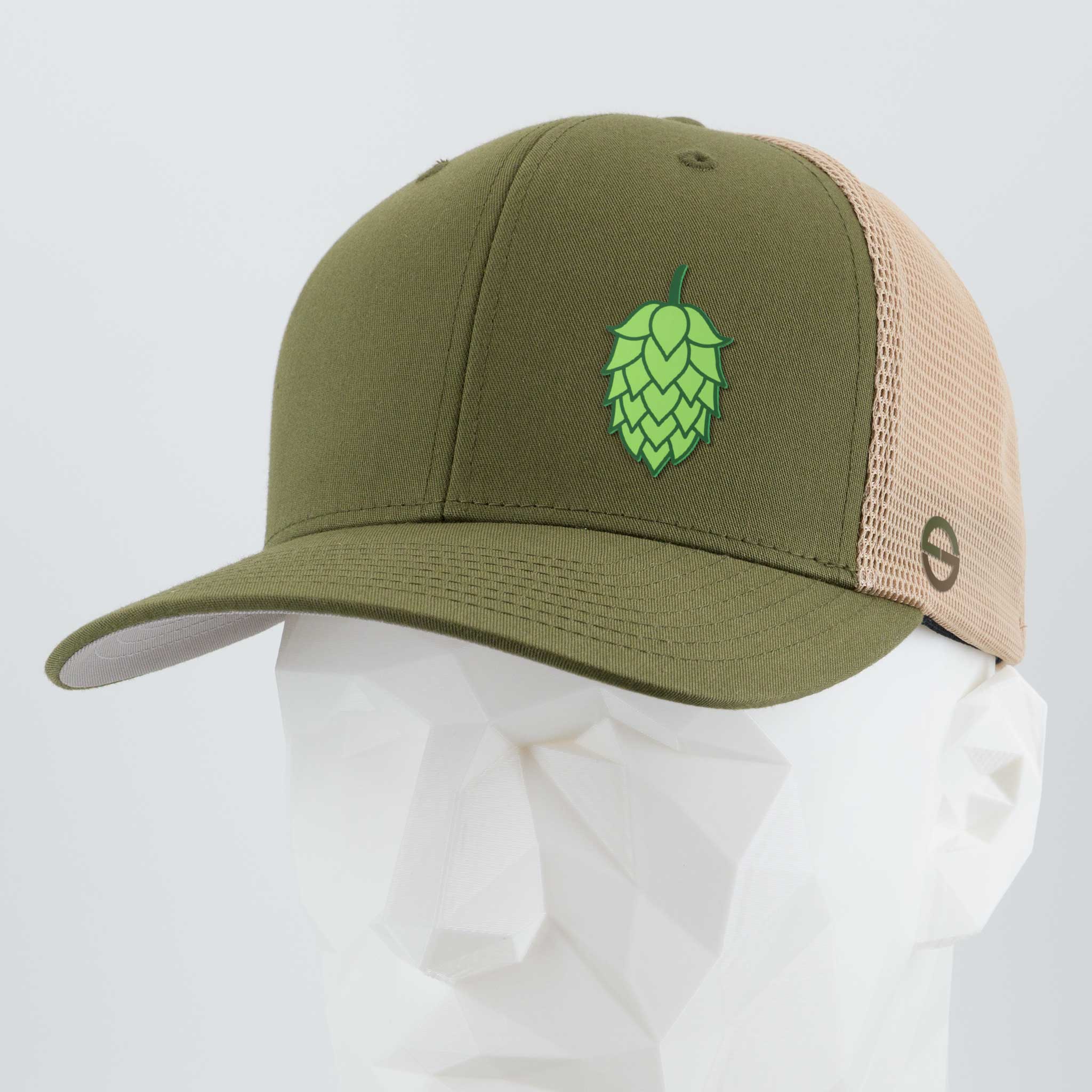 The Eternal Glyph Hop Cone (Silicone) - Flexfit® Mesh Trucker Cap in olive green and beige features a green hop cone on the front, shown on a faceted white mannequin head with a light gray background—ideal for beer lovers.