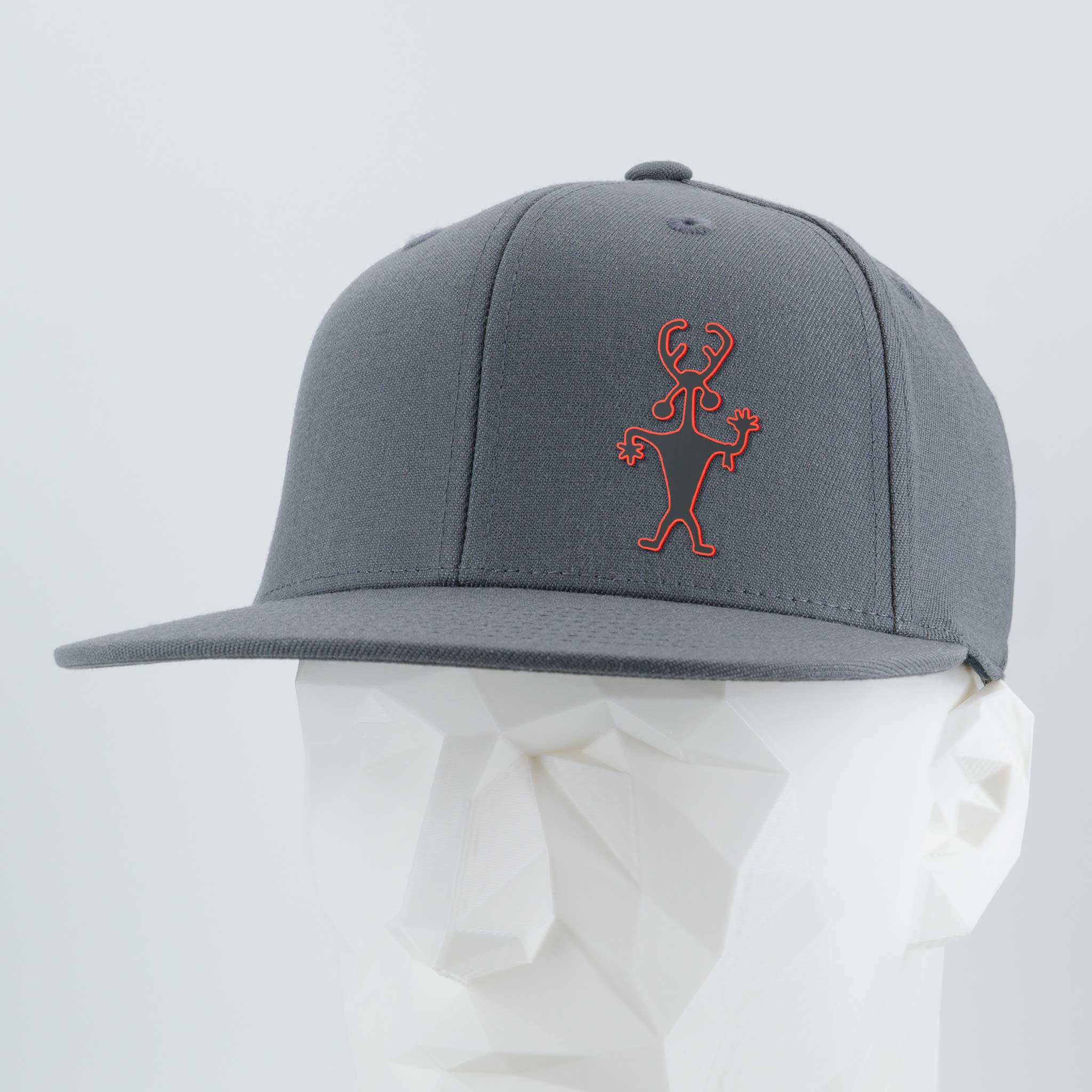 The Eternal Glyph Moab Shaman Petroglyph (Silicone) Flexfit® Flat Bill Premium Fitted Cap is gray, featuring a red outlined abstract figure inspired by the Moab Shaman, embroidered on the front and shown on a faceted white mannequin head.