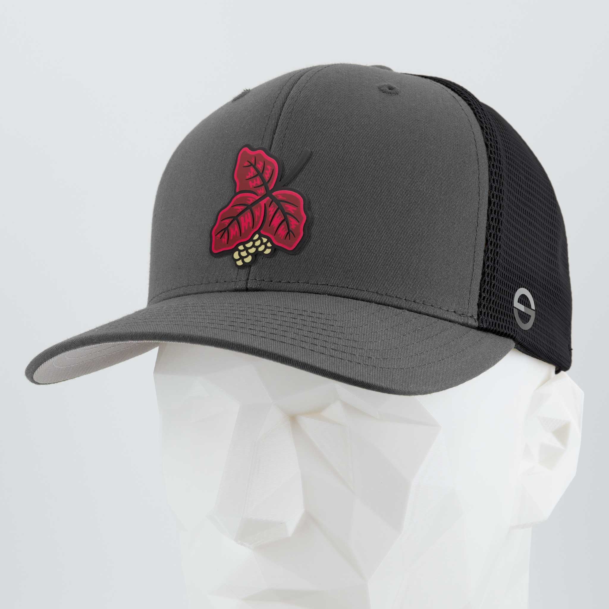 The Eternal Glyph Poison Oak (Double Layer Silicone) Flexfit® Mesh Trucker Cap in Dark Gray/Black features a red leaf and yellow berry embroidered design—evoking trail wisdom—shown on a white mannequin head. Ideal for outdoor explorers.