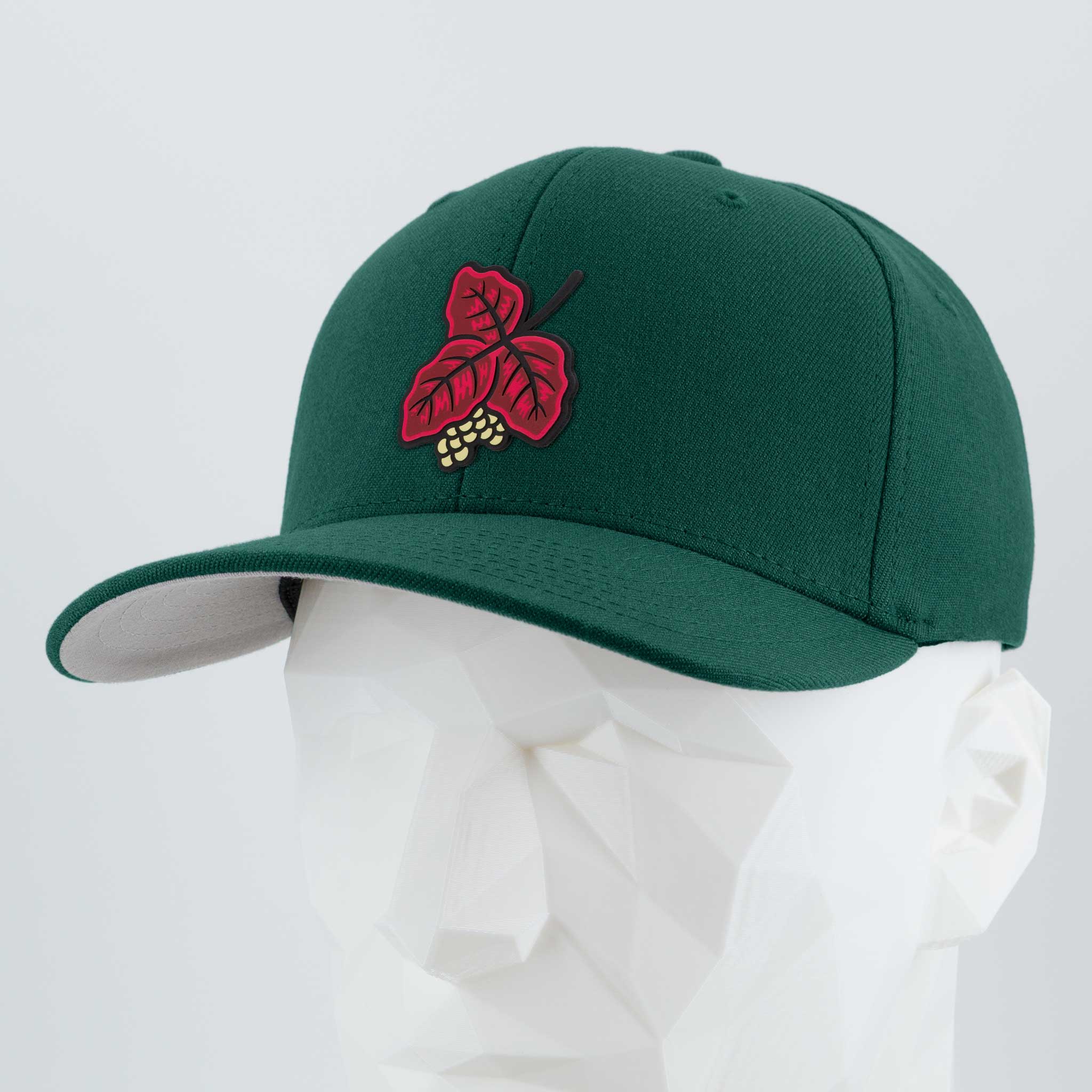 The Eternal Glyph Poison Oak (Double Layer Silicone) Flexfit® Premium Wool Blend Cap features a green base with a red leaf and yellow berry embroidered on the front, shown on a white geometric mannequin head.