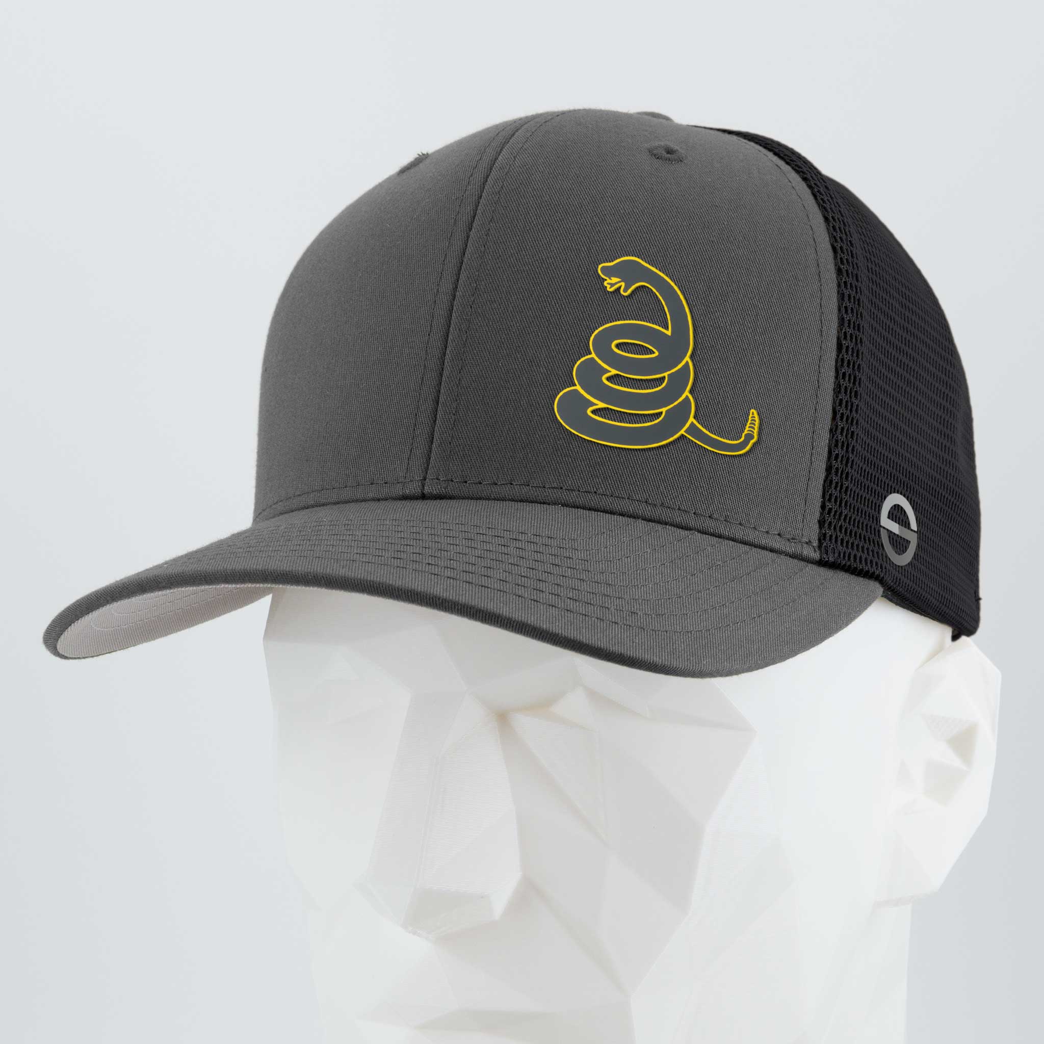 The Eternal Glyph Coiled Rattlesnake Silhouette (Silicone) Flexfit® Mesh Trucker Cap in gray and black features a yellow rattlesnake graphic inspired by the Gadsden flag, shown on a white geometric mannequin head.