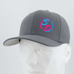 A dark gray Flexfit® Premium Wool Blend Cap from Eternal Glyph, featuring the Staying Driven silicone SD logo in pink and blue on the front, is displayed on a white geometric mannequin head against a light background, highlighting premium headwear for the Staying Driven fitness crew.
