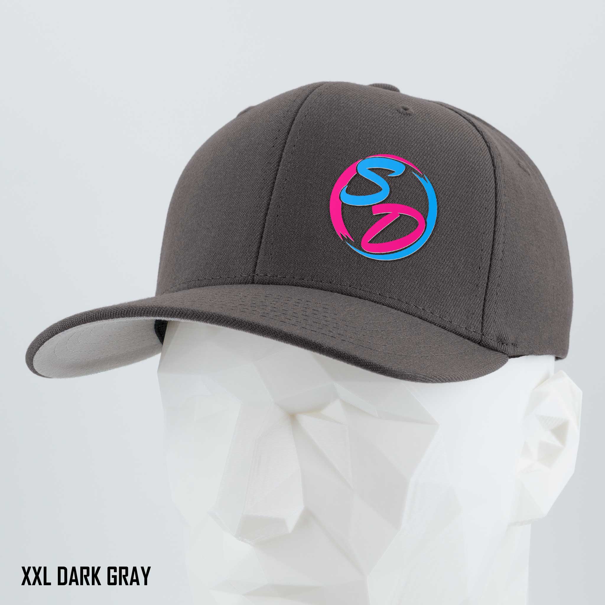 A dark gray Eternal Glyph Staying Driven (Silicone) Flexfit® Premium Wool Blend Cap, featuring a pink and blue SD logo on the front, is displayed on a white geometric mannequin head. Premium headwear crafted for the online fitness community. Text in the lower left corner reads XXL DARK GRAY.