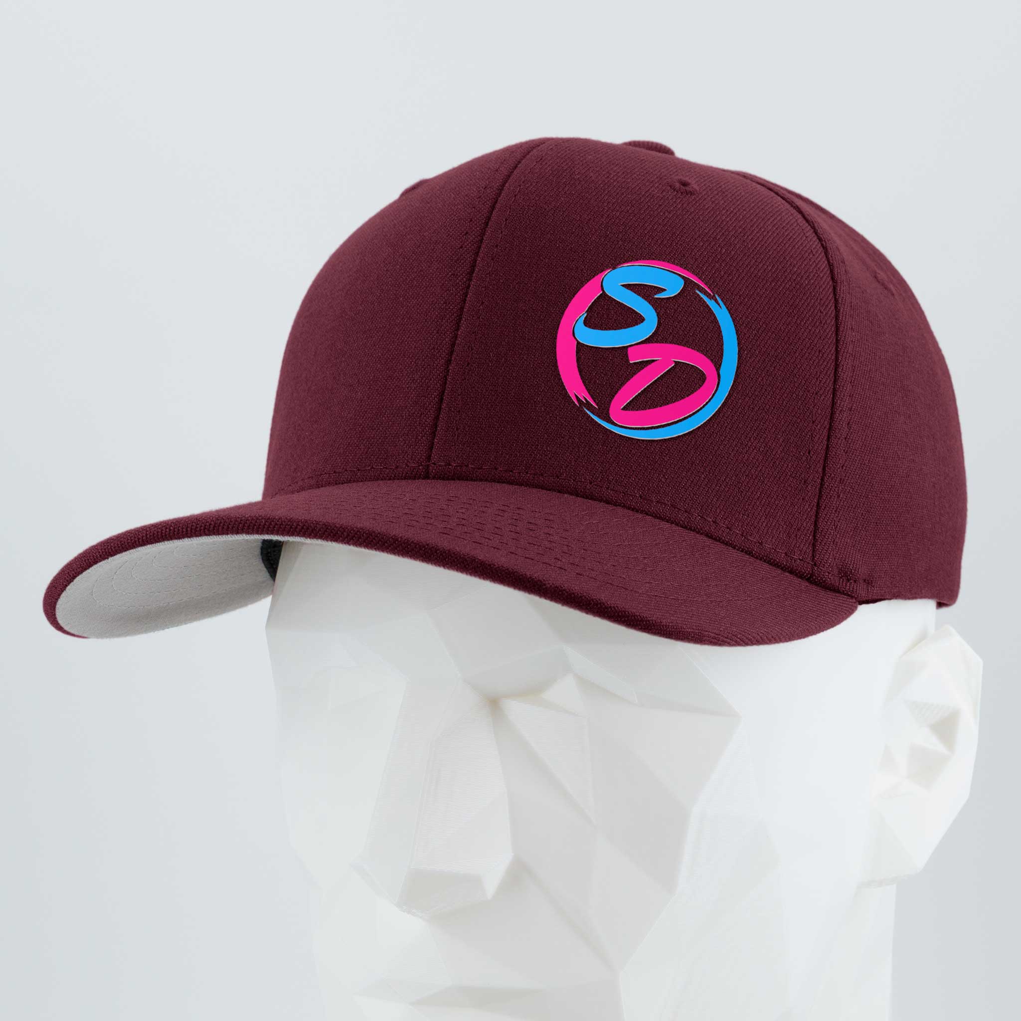 A faceted white mannequin wears the Eternal Glyph Staying Driven (Silicone) Flexfit® Premium Wool Blend Cap in maroon—premium headwear showcasing a vibrant SD logo in pink and blue on the front. Ideal for the Staying Driven fitness crew, set against a plain light gray background.