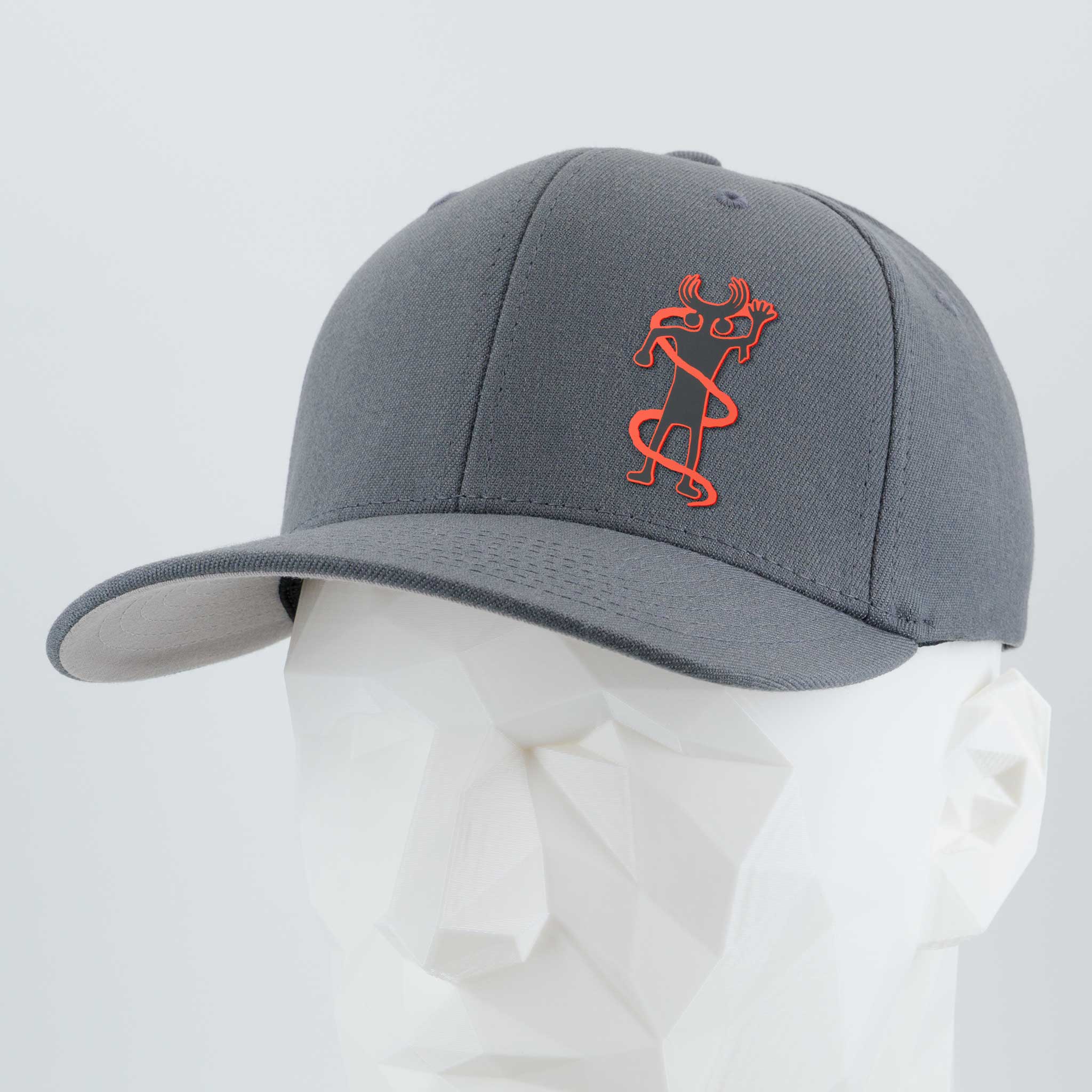 The Eternal Glyph Moab Shaman Petroglyph (Silicone) Flexfit® Premium Wool Blend Cap in dark gray features an orange stylized Moab Shaman design on the front and is displayed on a white geometric mannequin head.