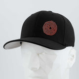 The Eternal Glyph Moab Spiral Petroglyph (Silicone) Flexfit® Premium Wool Blend Cap in black, featuring a red spiral design, is shown on a white geometric mannequin head against a plain light background.