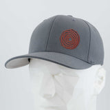 The Eternal Glyph Moab Spiral Petroglyph (Silicone) Flexfit® Premium Wool Blend Cap in dark gray features a red ancient-inspired spiral design on the front, shown on a white geometric mannequin head against a plain light background.