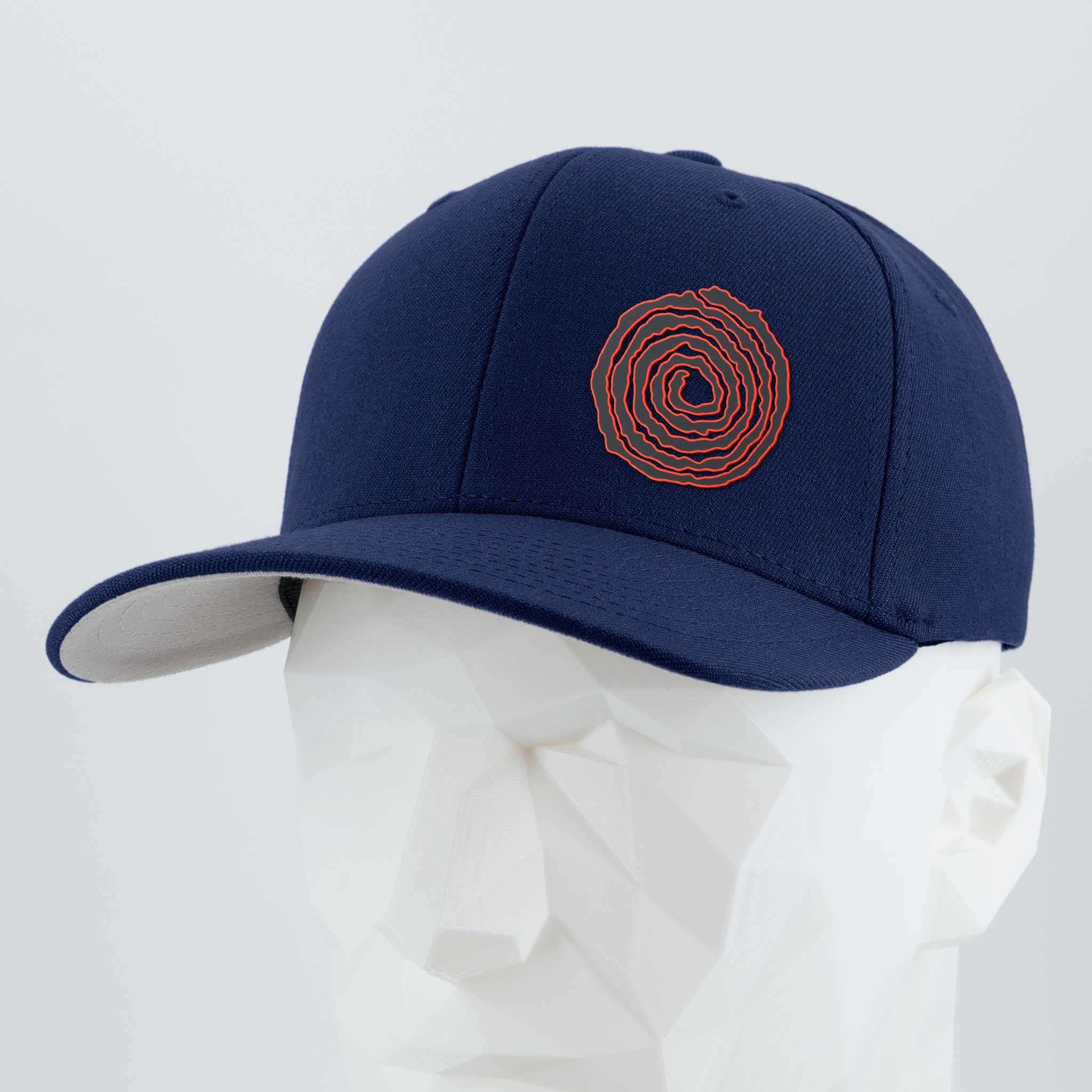 The Eternal Glyph Moab Spiral Petroglyph (Silicone) Flexfit® Premium Wool Blend Cap in navy, featuring a red spiral petroglyph design, is shown on a faceted white mannequin head against a light gray background.