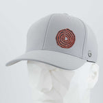 The Eternal Glyph Moab Spiral Petroglyph (Silicone) Flexfit® Cool & Dry Cap in silver features a red Spiral Petroglyph design on the front and a small gray side logo, shown on a faceted white mannequin head.
