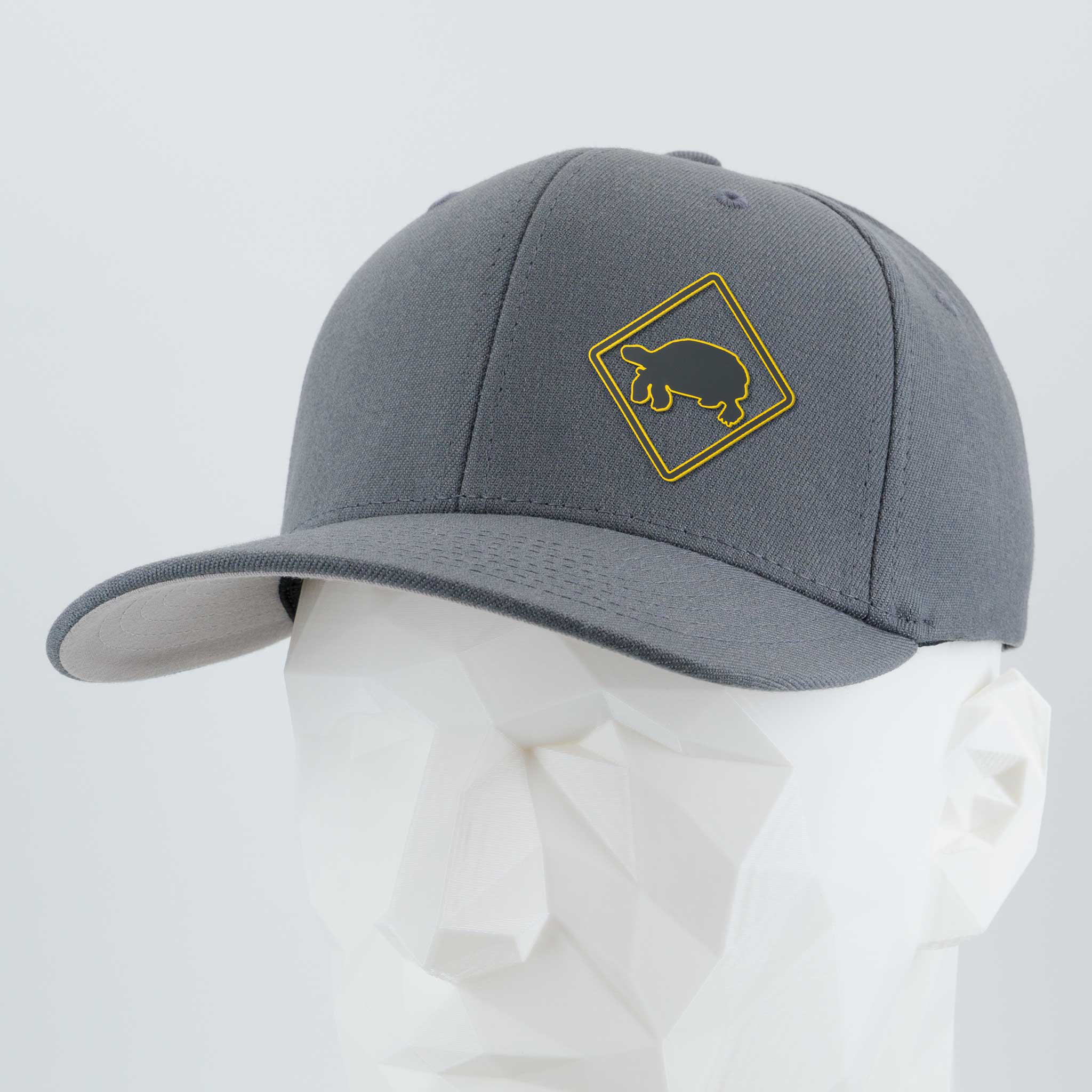 The Eternal Glyph Tortoise Crossing Sign (Silicone) Flexfit® Premium Wool Blend Cap features a yellow tortoise crossing emblem on gray, styled on a white geometric mannequin head.