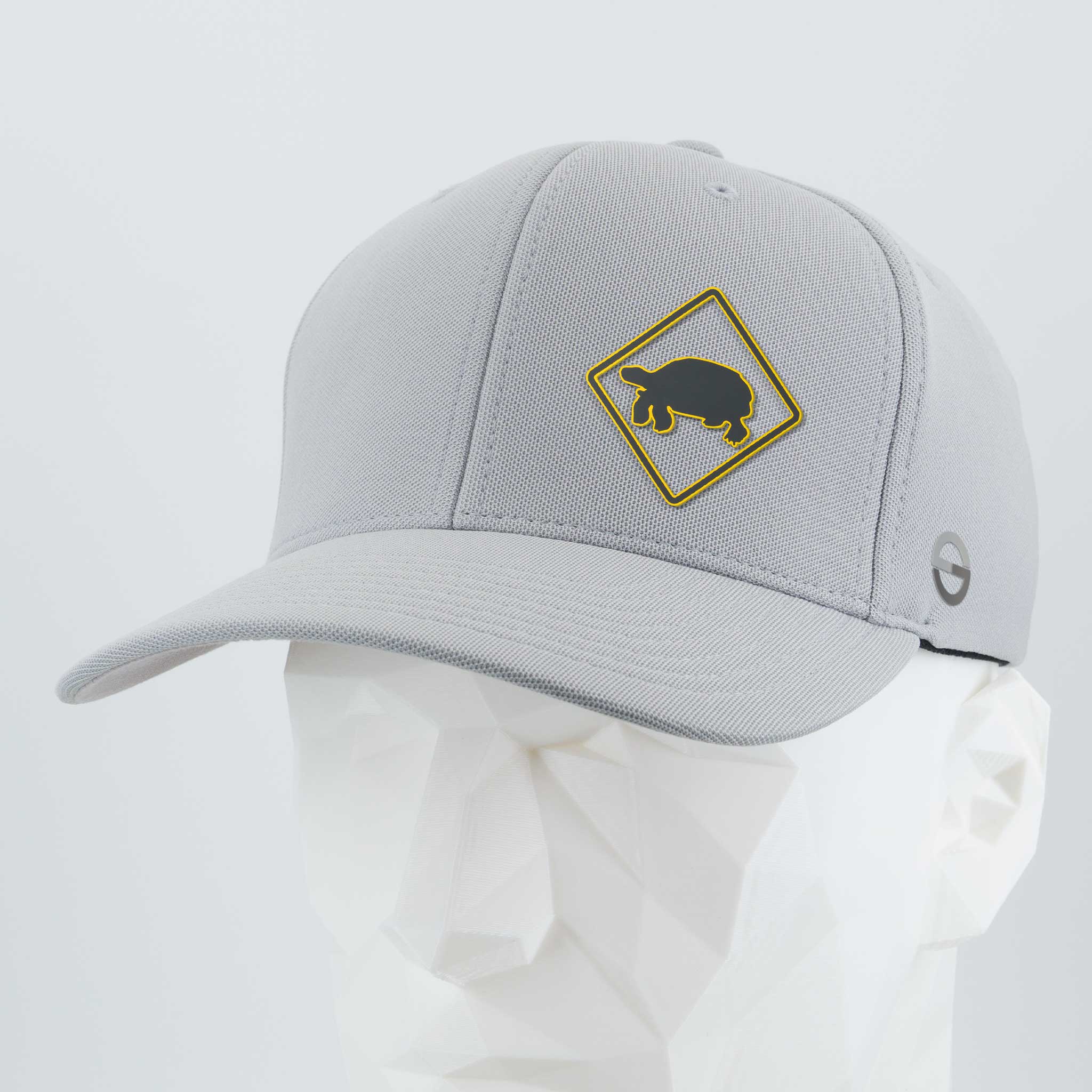 The Eternal Glyph Tortoise Crossing Sign (Silicone) Flexfit® Cool & Dry Cap is a light gray hat with a yellow turtle crossing sign on the front, shown on a white geometric mannequin head.
