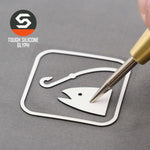 A hand peels an Eternal Glyph Fishing Trail Sign (Silicone) icon sticker from a gray surface. "TOUGH SILICONE GLYPH" appears next to a hexagonal logo, referencing the Flexfit® Mesh Trucker Cap by Eternal Glyph.