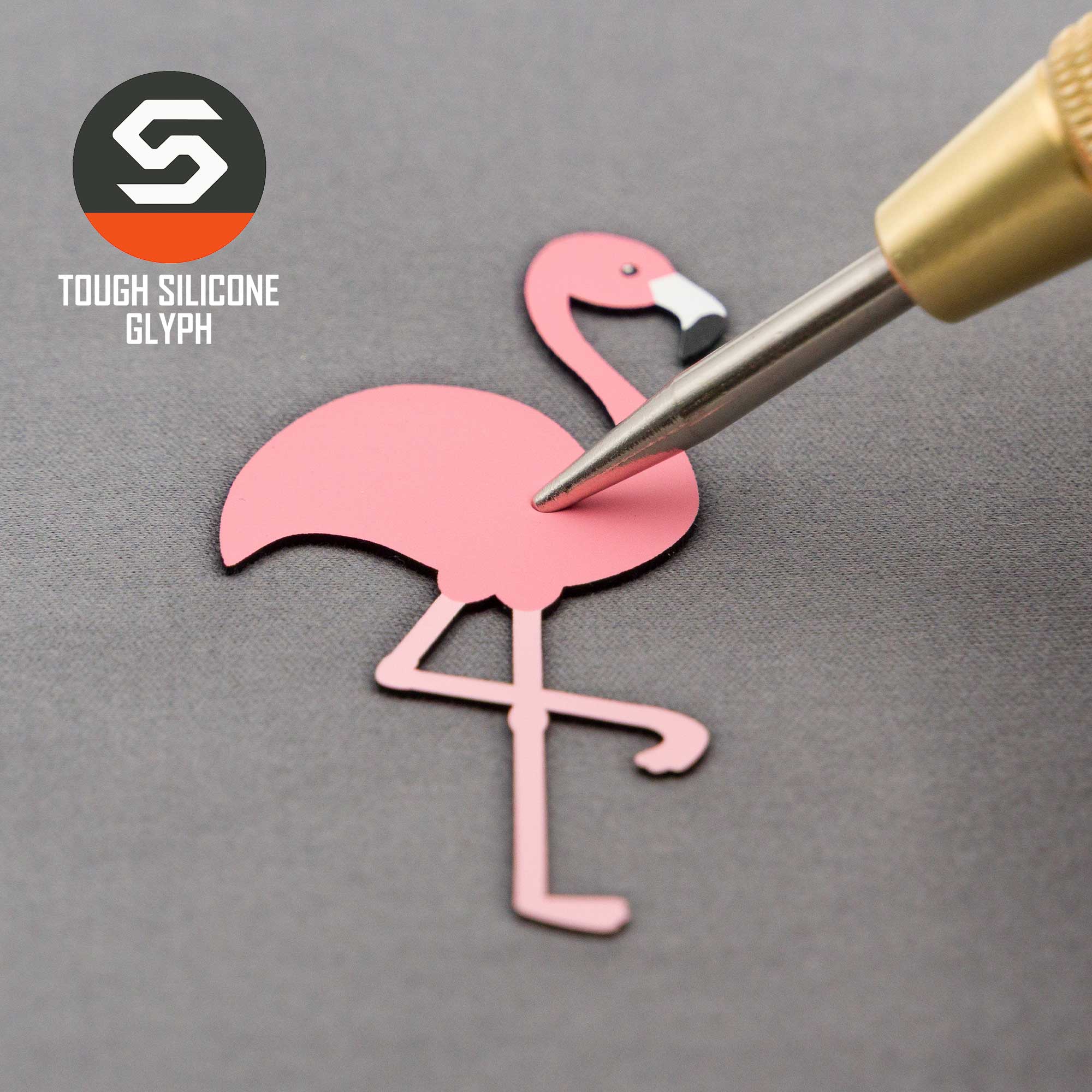 A close-up of a Pink Flamingo (Silicone) Flexfit® Flat Bill Premium Fitted Cap by Eternal Glyph, with the silicone patch being applied on a gray surface. The cap exudes summer vibes, featuring the logo and 'Tough Silicone Glyph' text in the corner.