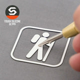 A hand holds a stylus toward a white silicone hiker symbol on a gray surface. Top left: Eternal Glyph logo and “Hiker Trail Sign (Silicone) – Flexfit® Mesh Trucker Cap.”.