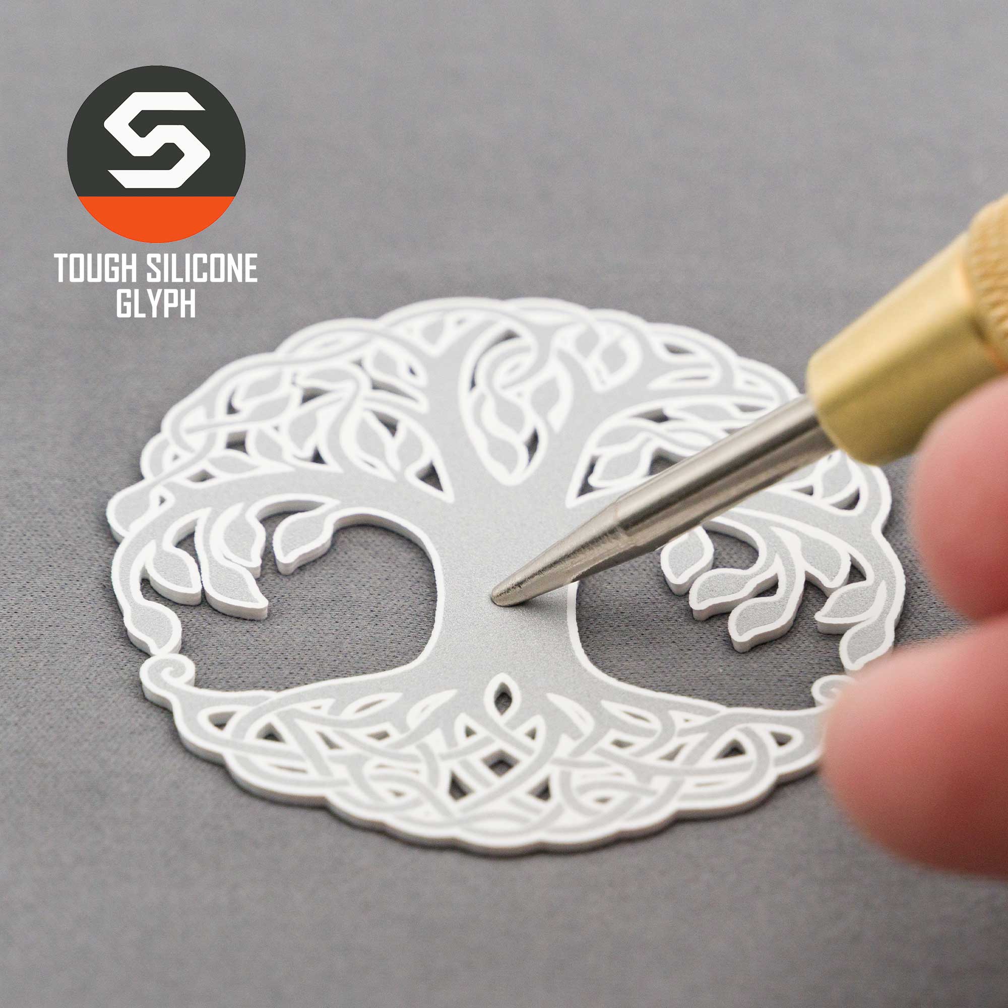 A hand presses a tool into the silver silicone Tree of Life Yggdrasil design on a gray surface. "Eternal Glyph" and "TOUGH SILICONE GLYPH" appear in the top left, highlighting the Flexfit® Cool & Dry Cap: Tree of Life, Yggdrasil.
