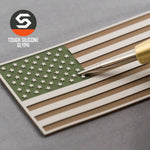 A pen points at an Eternal Glyph American Flag, Camo (Double Layer Silicone) patch in olive, tan, and white on a gray surface. The Tough Silicone Glyph logo at the top left evokes rugged outdoor gear.