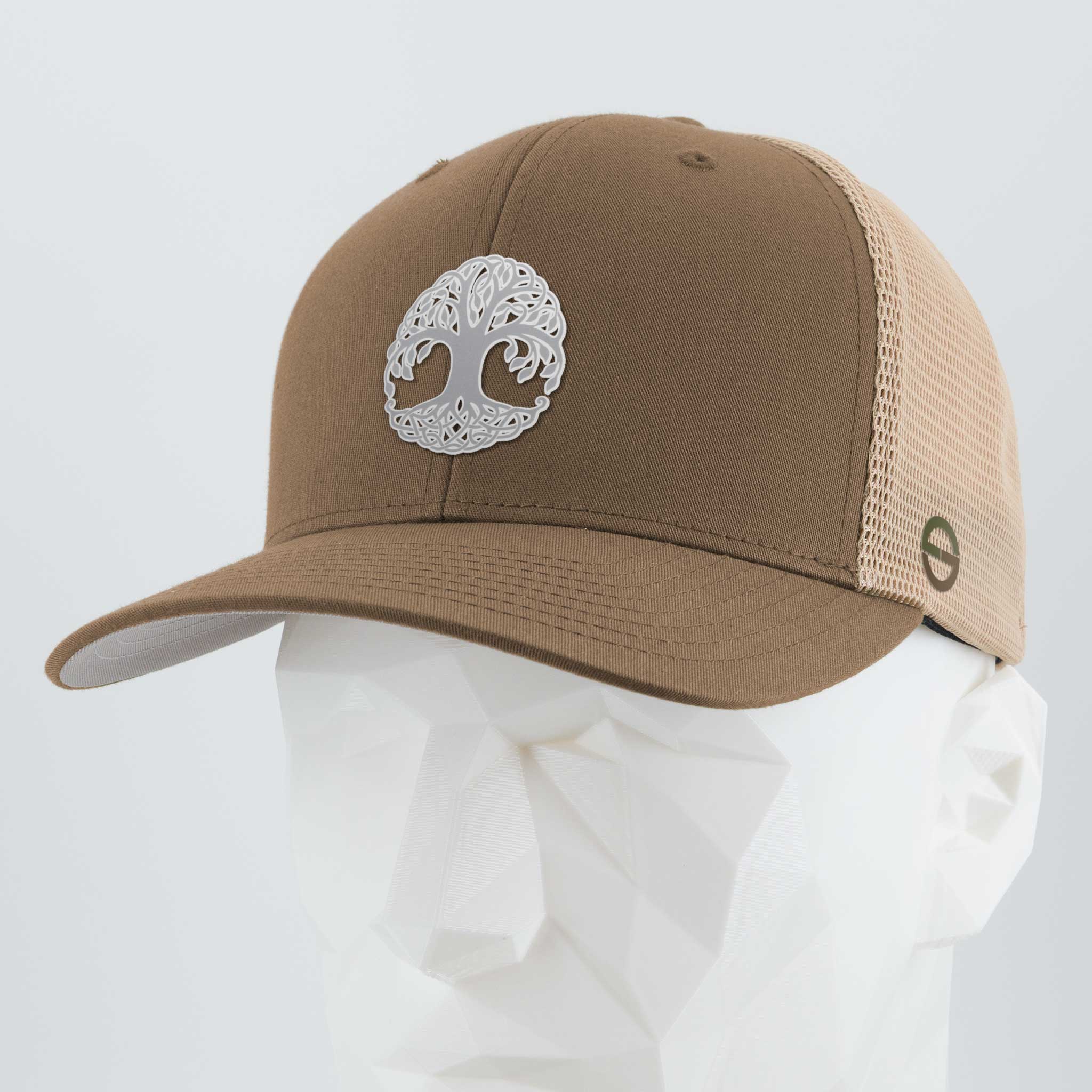 The Eternal Glyph Tree of Life Yggdrasil Metallic Silver Flexfit® Mesh Trucker Cap features a brown mesh back, curved brim, and a silver silicone Yggdrasil design on the front, shown on a white geometric mannequin head.