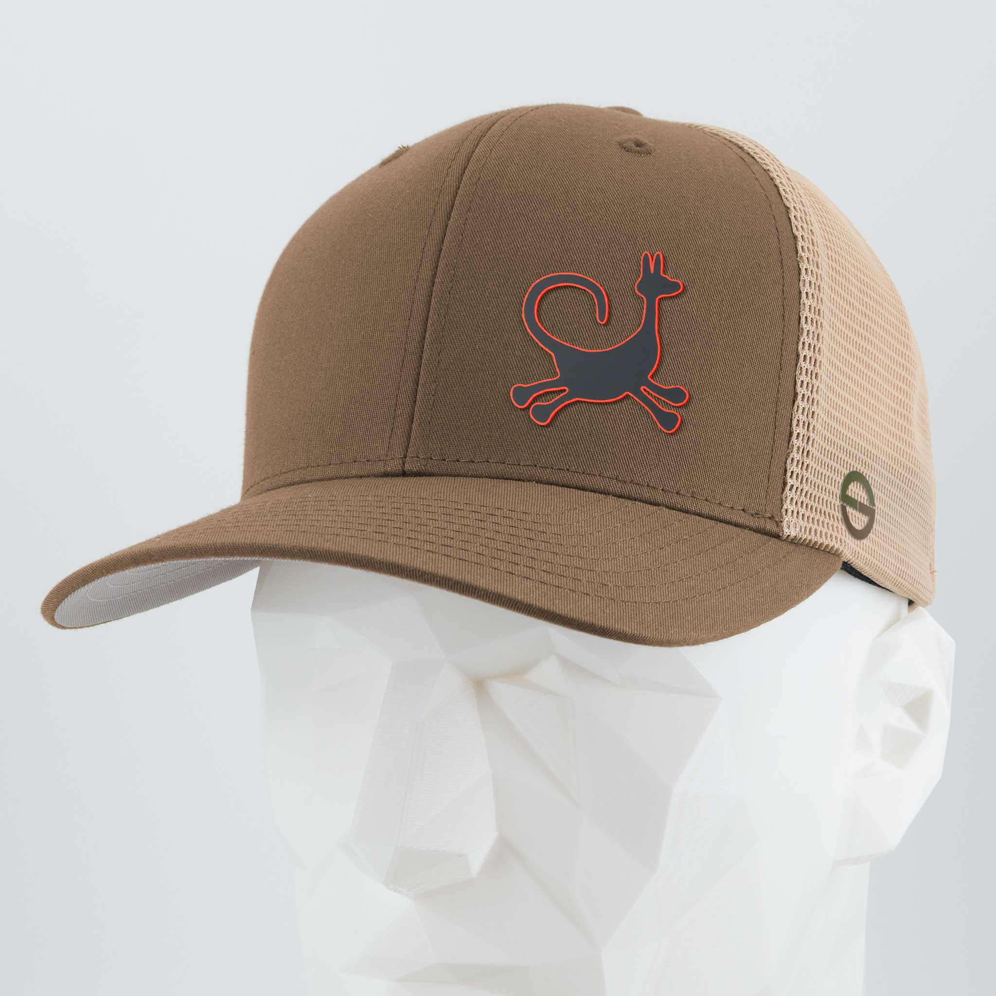 The Eternal Glyph Moab Trickster Coyote Petroglyph Flexfit® Mesh Trucker Cap in Coyote/Khaki features a silicone coyote symbol on the front and a mesh back, inspired by the spirit of Moab, Utah. Displayed on a white geometric mannequin head.