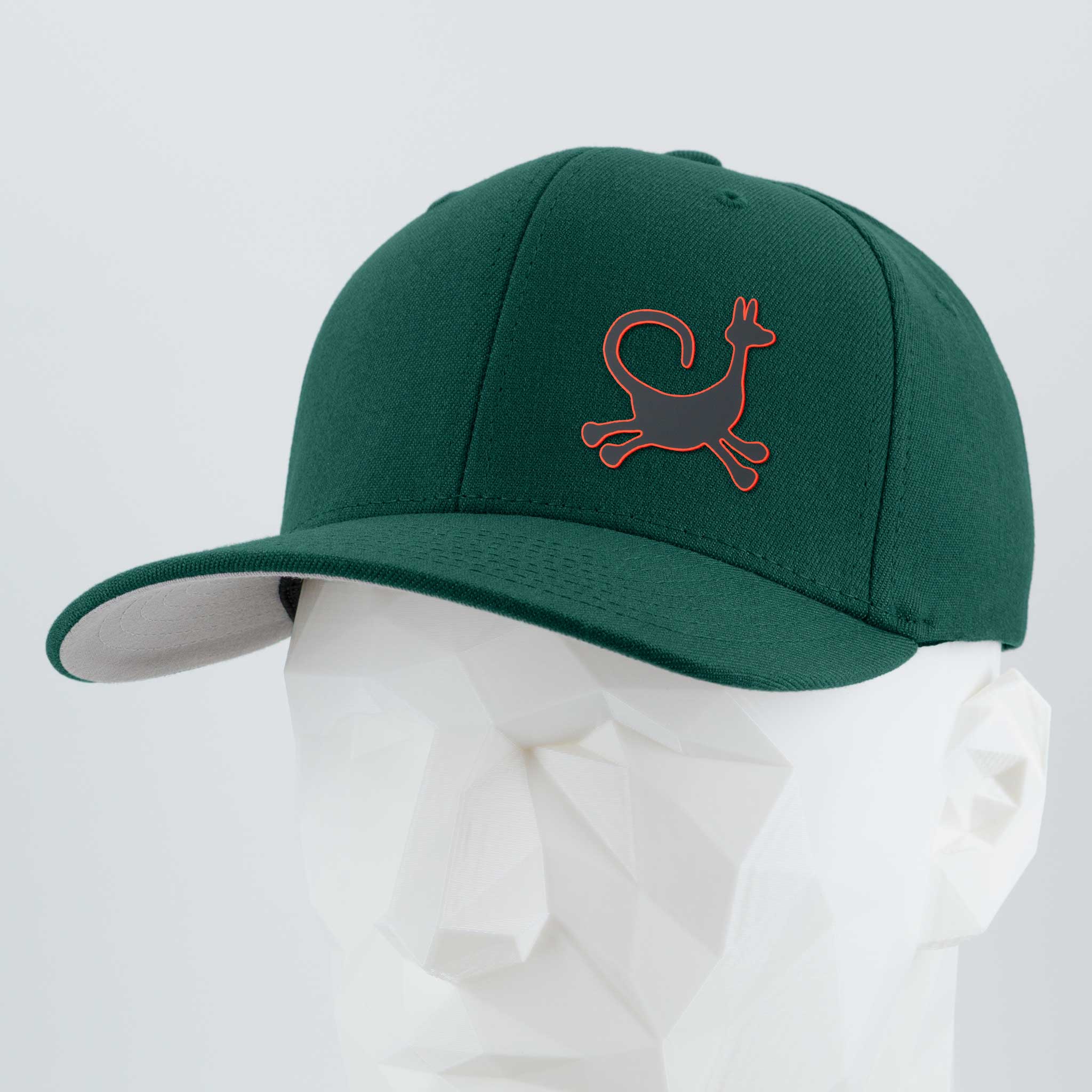 The Eternal Glyph Moab Trickster, Coyote Petroglyph (Silicone) Flexfit® Premium Wool Blend Cap, in dark green with a red petroglyph logo, is displayed on a white geometric mannequin head against a plain light gray background.