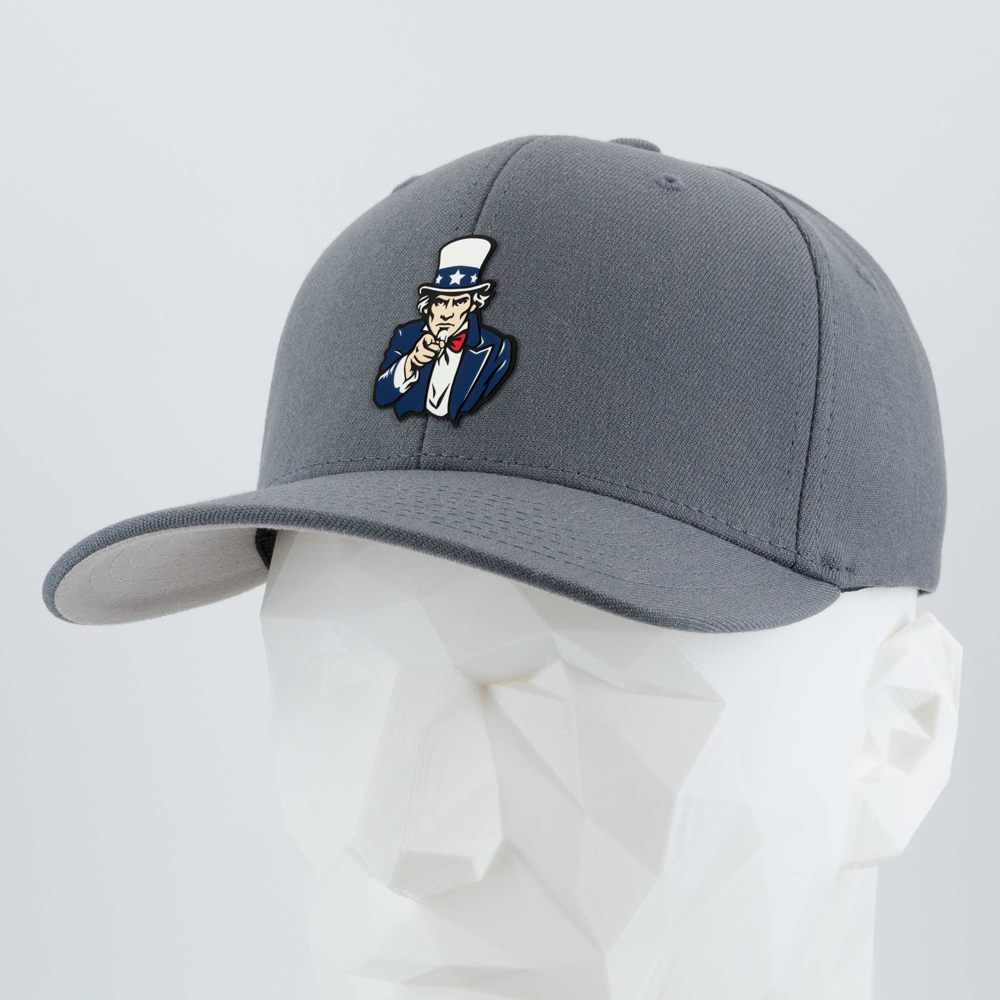 The Eternal Glyph "Uncle Sam, I Want You (Silicone)" Flexfit® Premium Wool Blend Cap in Dark Gray features a vibrant Uncle Sam patch and is shown on a white geometric mannequin head.